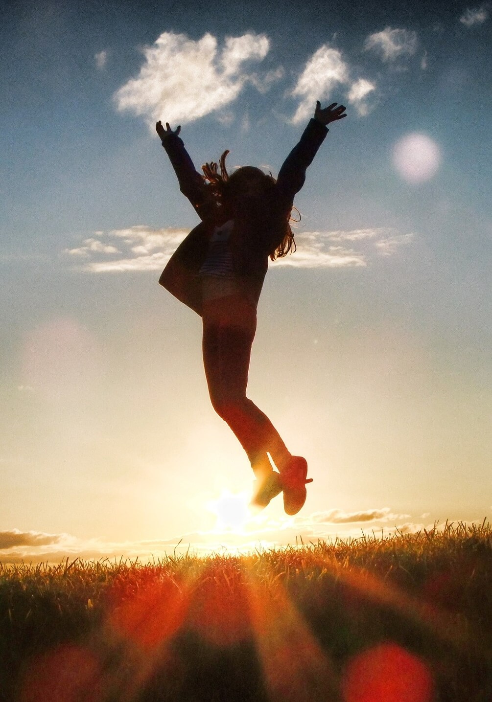 Jeune femme sautant dans les airs au coucher de soleil