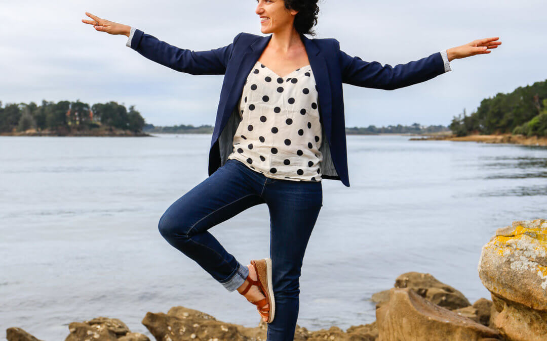 Femme faisant la posture de yoga de l'arbre devant la mer